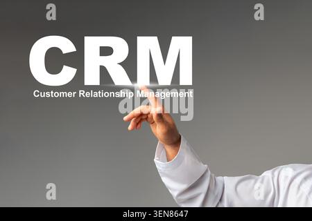 Hand pointing to CRM letters representing customer relationship management concept Stock Photo