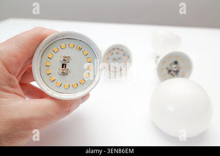 Man hand holding the broken white LED lamp, isolated on white background. Broken white led lamp circuits. Broken led light components. Stock Photo