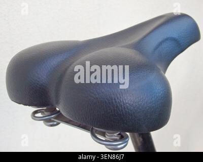 Black leather bicycle seat close-up. Bicycle seat on a white background. Cropped Image Of Bicycle On Street Stock Photo
