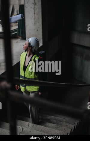 Female construction worker in hard hat and safety vest inspecting an unfinished building site Stock Photo