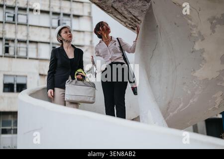 Two female architects inspecting a concrete spiral staircase during a construction site visit and discussion Stock Photo