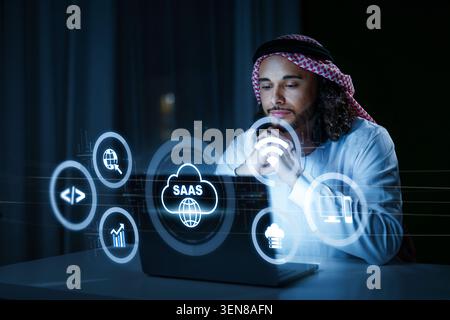 Man using laptop to explore SaaS concepts in a dark room at night Stock Photo
