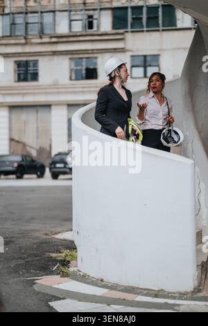 Businesswomen in hard hats inspecting an urban construction site and discussing project plans on stairs Stock Photo