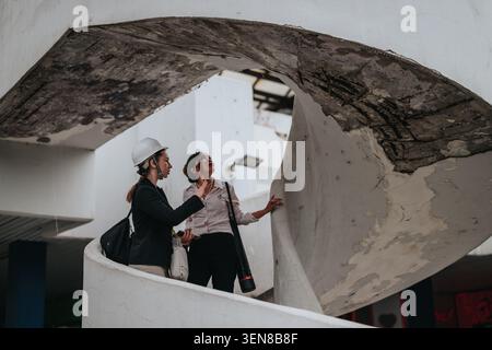 Engineer and inspector examining damaged concrete spiral staircase during building inspection and assessment Stock Photo