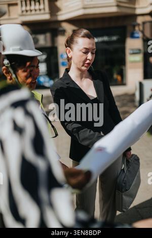 Businesswoman reviewing construction plans with engineers on site during an outdoor project meeting Stock Photo