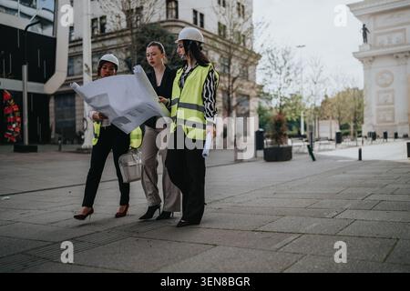 Three women construction architects reviewing blueprints on an urban street in teamwork discussion Stock Photo