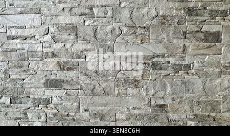 tone cladding wall made of natural rocks with shades between white, brown and gray. Background and texture. Stock Photo