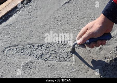 A worker spreading mortar evenly using a trowel Stock Photo