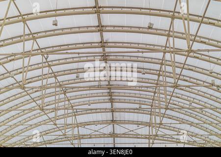 Industrial greenhouse structure featuring curved metal beams and translucent roof material showcasing robust framework and natural light diffusion enh Stock Photo