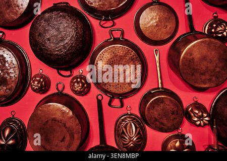 antique copper kitchen pots, pans, and molds arranged against a solid background Stock Photo