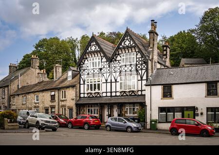 Wide horizontal street scene showing the historic black and white timber-framed property with parked cars in Tideswell village center Stock Photo