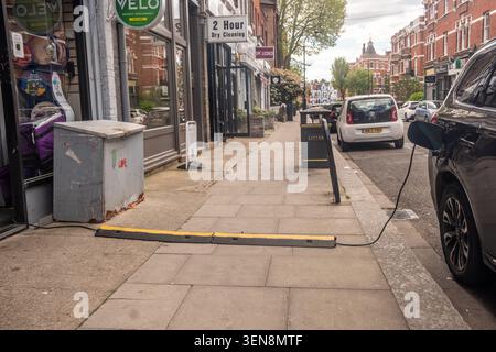 LONDON - APRIL 18, 2026: HAMMERSMITH – EV charging cable across pavement Stock Photo