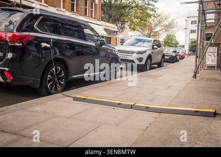 LONDON - APRIL 18, 2026: HAMMERSMITH – EV charging cable across pavement Stock Photo