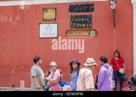 Antigua Guatemala,UNESCO World Heritage Site,Galeria La Merced,ATM,cafe sign,business signs,street scene,visitors,tourists,men,women,adults,standing,w Stock Photo