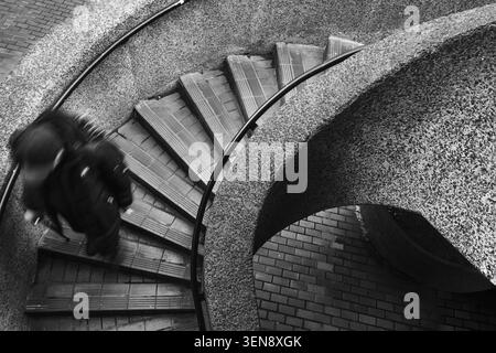 A man walking down some spiral stairs Stock Photo