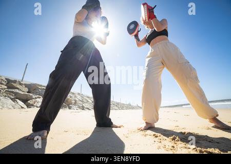 Women training boxing on a beach learning fitness Stock Photo