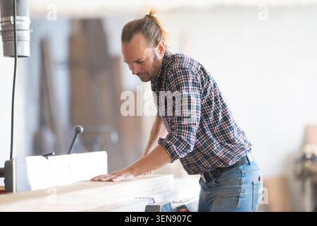 Woodworker carefully shaping wood using a planer machine Stock Photo