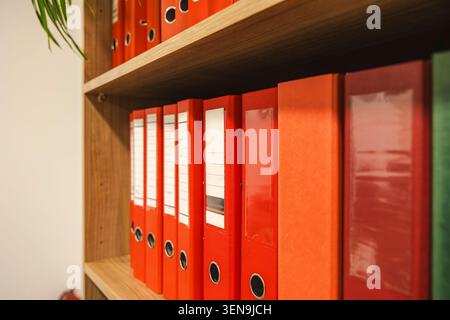 Colorful ring binders on wooden office shelves closeup. Concept: document archiving Stock Photo
