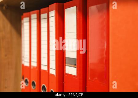 Red ring binders on wooden shelf closeup in corporate office. Concept: tax audit Stock Photo