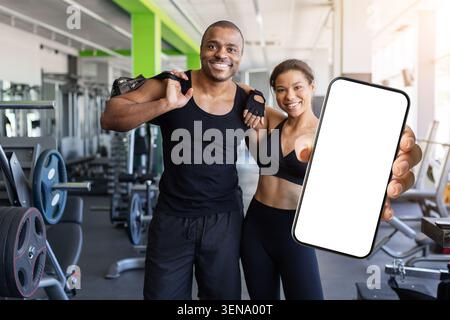 Young black in gym presenting smartphone with blank screen Stock Photo