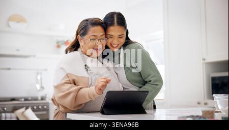 Baking, old woman and daughter with tablet in kitchen, laughing and searching for recipe on website. Happy people, online and meal prep with senior Stock Photo