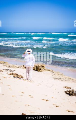 A woman in white outfit on an empty beach in Hawaii Stock Photo