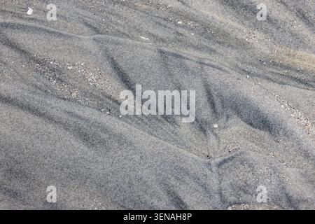 Black and gray pattern in the sand on a sandy beach, background Stock Photo