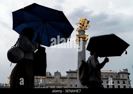 People walk with umbrellas in front of a 
