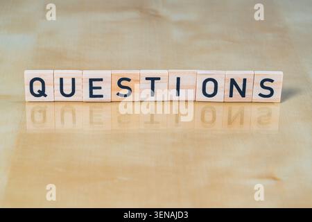 Wooden tile with the word Questions printed on and reflected on below surface, business meeting or presentation last slide element Stock Photo