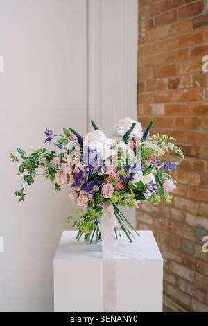 Elegant Floral Bouquet on White Pedestal with Brick Wall Background Stock Photo