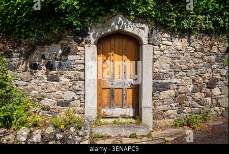 Old fashioned external wooden door in a stone built wall, Bovey Tracey, Devon Stock Photo