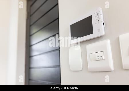Monitor is showing blank screen while handset and dimmer are resting on wall beside louvered door Stock Photo