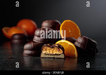 Cookies with dark chocolate and orange marmalade. Chocolate dessert with slices of fresh oranges on a black background. Stock Photo