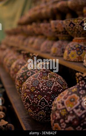 Close-up of a handcrafted ceramic ornament featuring intricate floral patterns and colorful traditional designs displayed on a market shelf. Selective Stock Photo