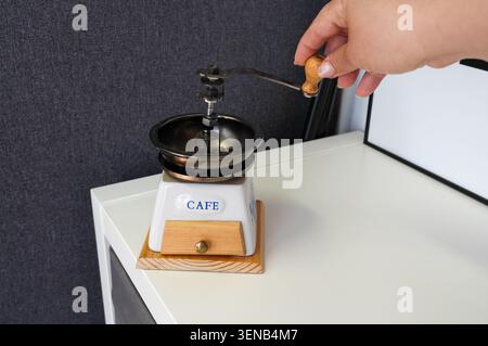 Coffee grinder with the word coffee written on it. A woman's hand grinds coffee Stock Photo