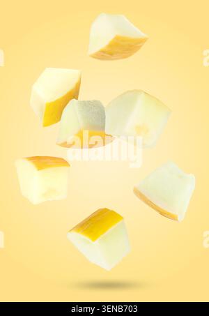 Sweet melon pieces falling against orange background Stock Photo