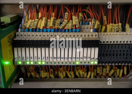 Row of industrial interface relays with active green LED indicators on control panel terminal board Stock Photo