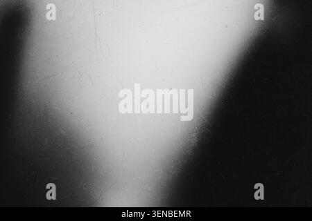 Dark grunge texture background with film grain dust scratches and bright light leak in center Stock Photo