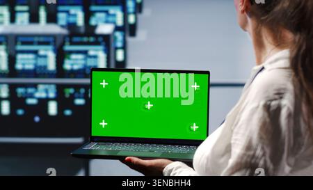 Licensed tech support in server farm housing high end supercomputers capable of quickly and efficiently performing complex computations and data analysis, using mockup laptop to remove dangers. Stock Photo