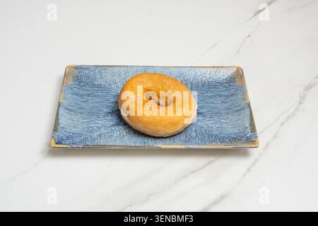 An intimate scene with a stack of two or three donuts on a porcelain plate, next to steaming coffee and a newspaper, capturing the essence of a pleasu Stock Photo