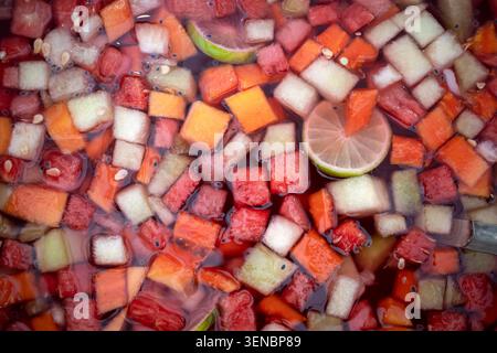 Close up of a refreshing drink with a mix of clear ice cubes and fresh fruit slices, emphasizing vibrant fruit colors. Stock Photo