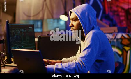 Hacker using VPN and darknet as anonymity tools to mask his online identity while committing data breaches, Cybercriminal in underground bunker masking his location hacking into servers. Stock Photo