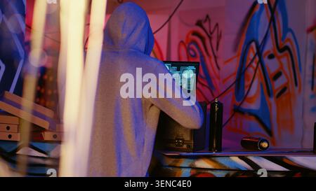 Close-up shot of hacker in underground bunker using network vulnerabilities to exploit servers, trying to break computer systems at night, African American cybercriminal breaching networks. Stock Photo