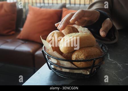 Hand reaching for bread rolls in a cafe setting Stock Photo