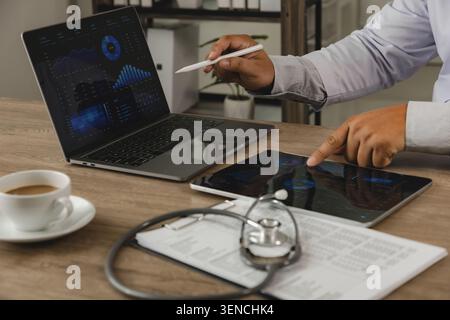 Business intelligence analytics dashboard displayed on laptop and tablet in healthcare office. Data visualization, KPI monitoring, financial reporting Stock Photo