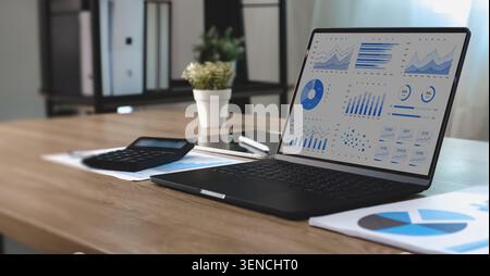 Business dashboard displaying data and graphs on a laptop with financial reports and calculator, supporting performance analysis, reporting workflow, Stock Photo