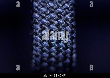 Close up macro shot of a blue and black braided cable on a black background. The braided cable is a USB-C cable from a power bank Stock Photo