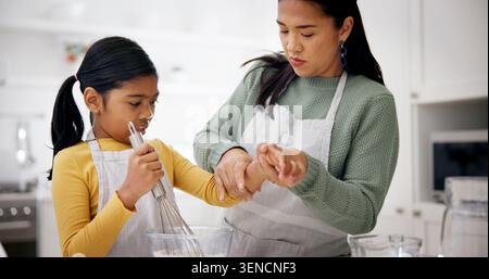 Mom, girl and baking in kitchen with help, teaching recipe and bonding with dessert in home. Learning, kid and mother with rolling up sleeves Stock Photo