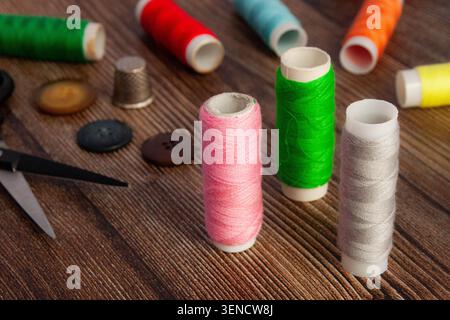 Sewing Thread Spools With Buttons And Scissors On Wooden Table Stock Photo