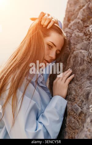 Woman rock sunlight portrait of a young woman leaning against a stone cliff during sunset with warm lens flare Stock Photo